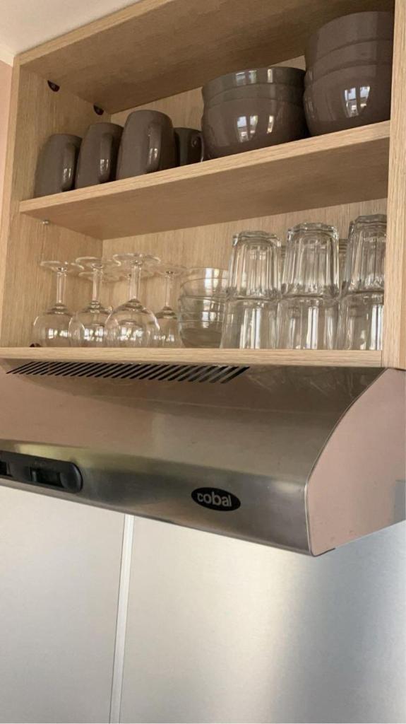 un placard contenant des verres et d'autres plats dans l'établissement Mobil-home Camping - La Marine - Grau du Roi, au Grau-du-Roi