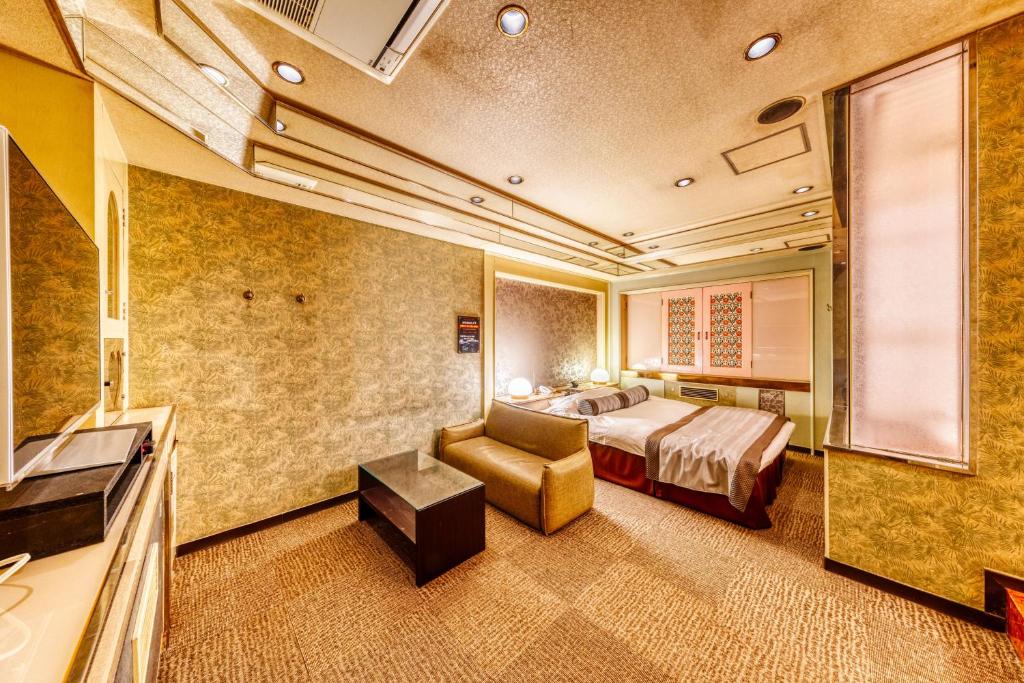 une chambre d'hôtel avec un lit et une chaise dans l'établissement Hotel Liebhaber -Adult Only, à Hirakata