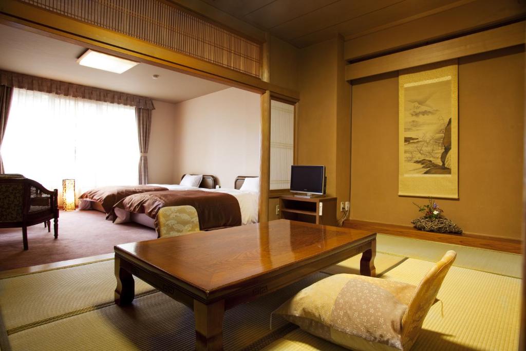 une chambre avec un lit et une table dans une pièce dans l'établissement Tokinenoyado Yunushi Ichijoh, à Shiroishi