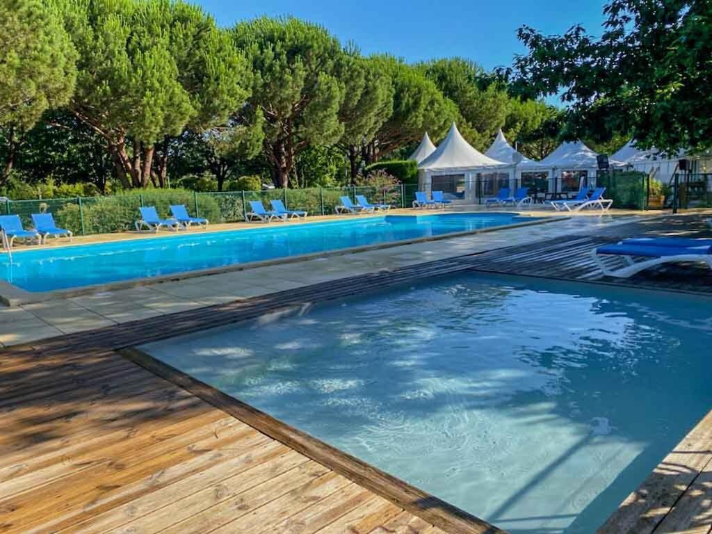 - une piscine avec une terrasse en bois, des chaises et des arbres dans l'établissement Camping Le Braou - Maeva, à Audenge