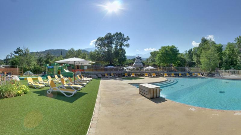 une grande piscine avec des chaises longues et une piscine. dans l'établissement Camping Les Airelles - Maeva, à Baratier