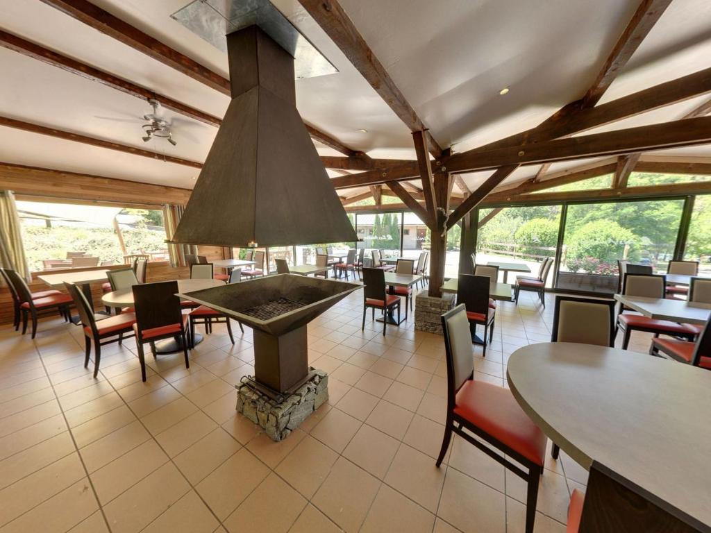 un restaurant avec des tables et des chaises et une cheminée dans l'établissement Camping Les Airelles - Maeva, à Baratier