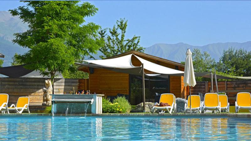 un groupe de chaises et de parasols à côté d'une piscine dans l'établissement Camping Les Airelles - Maeva, à Baratier