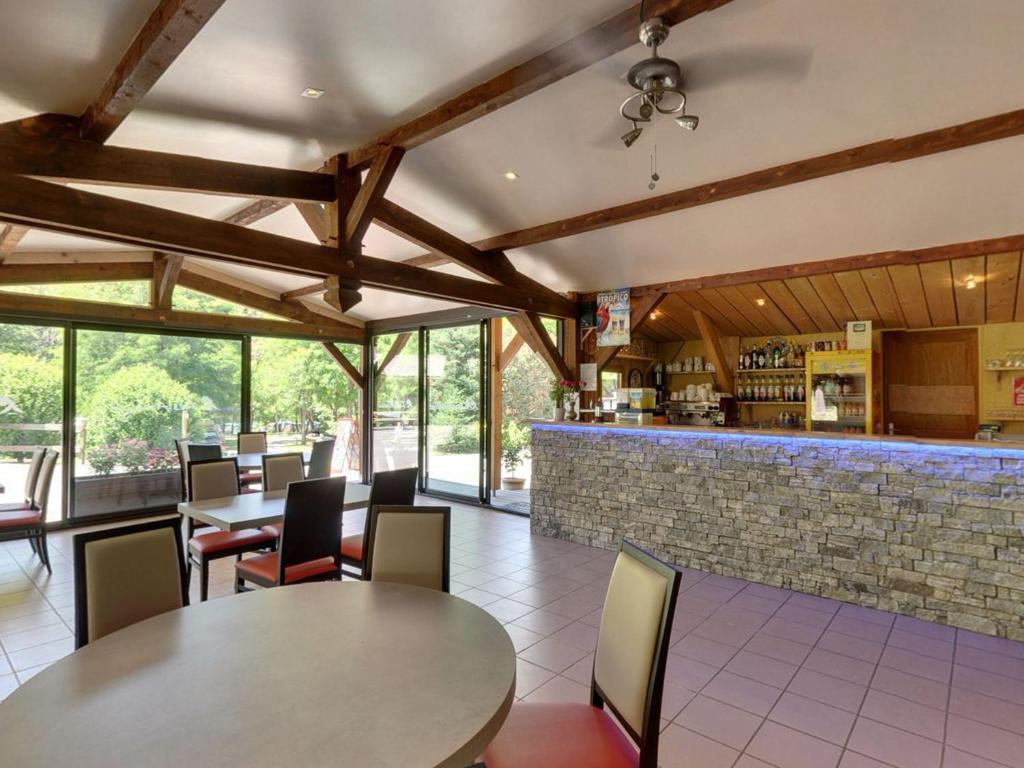 un restaurant avec des tables et des chaises et un bar dans l'établissement Camping Les Airelles - Maeva, à Baratier