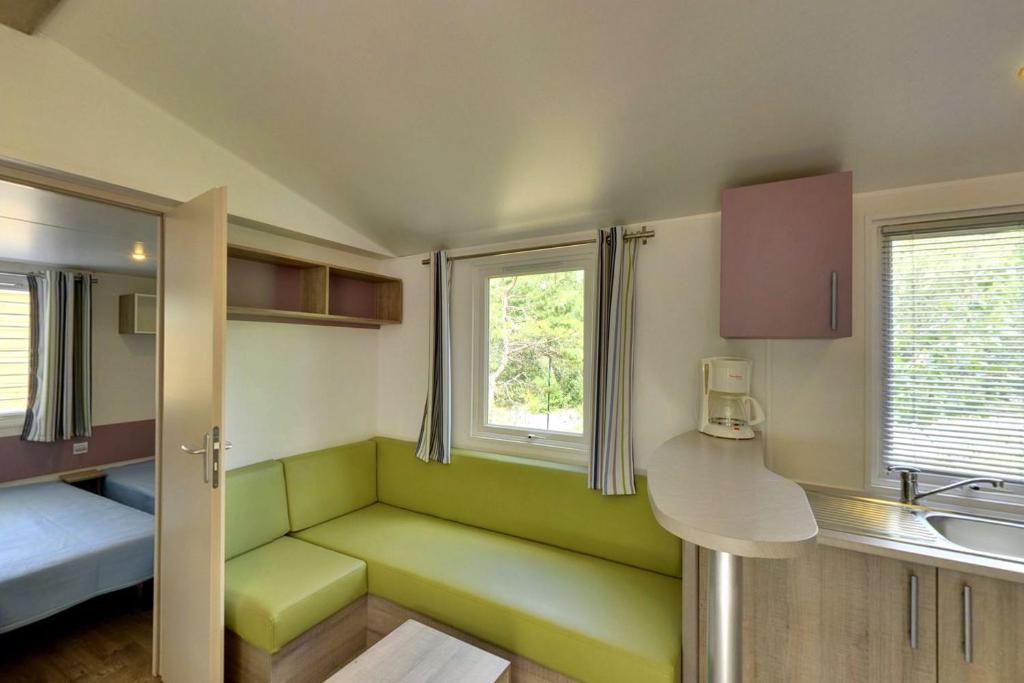 Cette petite chambre dispose d'un canapé vert et d'un lavabo. dans l'établissement Camping Les Airelles - Maeva, à Baratier