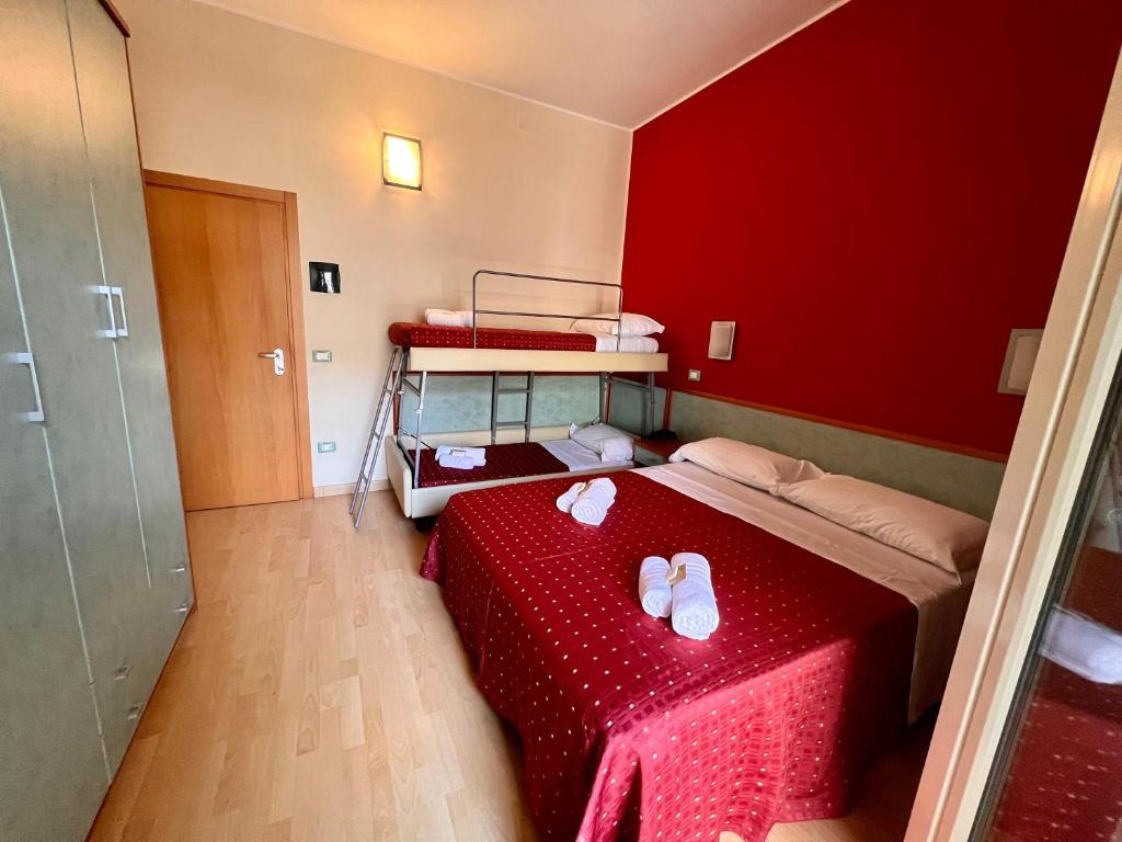 Cette chambre rouge comprend un lit avec des tongs. dans l'établissement Hotel Villa Tina, à Cesenatico