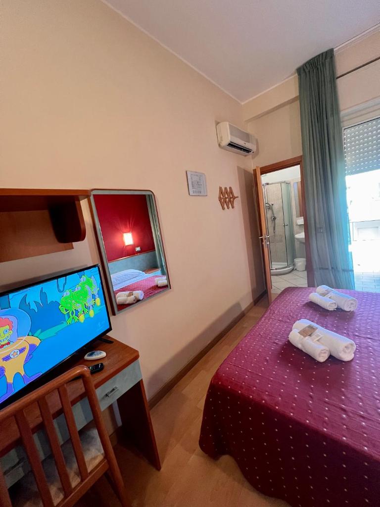 Cette chambre dispose d'une télévision et d'un lit avec un couvre-lit rouge. dans l'établissement Hotel Villa Tina, à Cesenatico