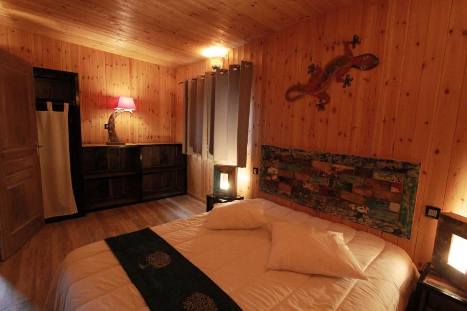 une chambre avec un lit dans une pièce aux murs en bois dans l'établissement Cerza Safari Lodge, à Hermival-les-Vaux