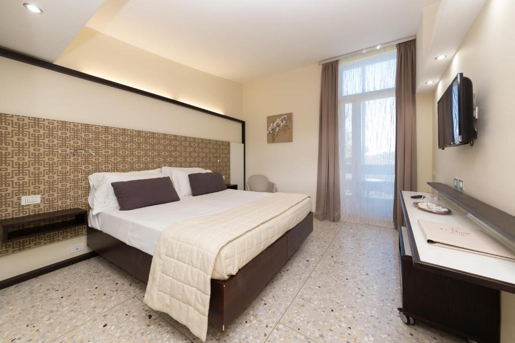 une chambre d'hôtel avec un grand lit et une télévision dans l'établissement Valtur Baia del Gusmay Beach Resort, à Peschici