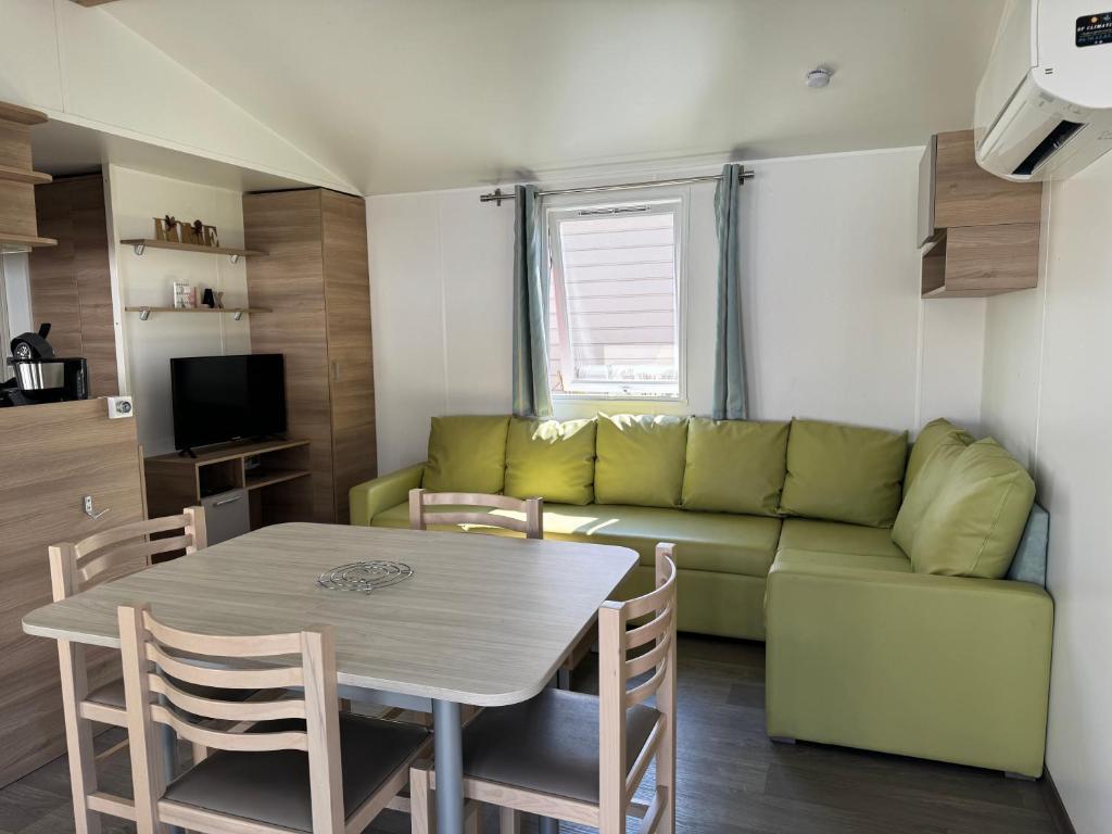 - un salon avec une table et un canapé vert dans l'établissement Camping le Neptune, à Argelès-sur-Mer