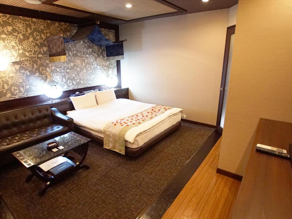 une chambre d'hôtel avec un lit et un canapé dans l'établissement Hotel FirstWood 成田店, à Narita