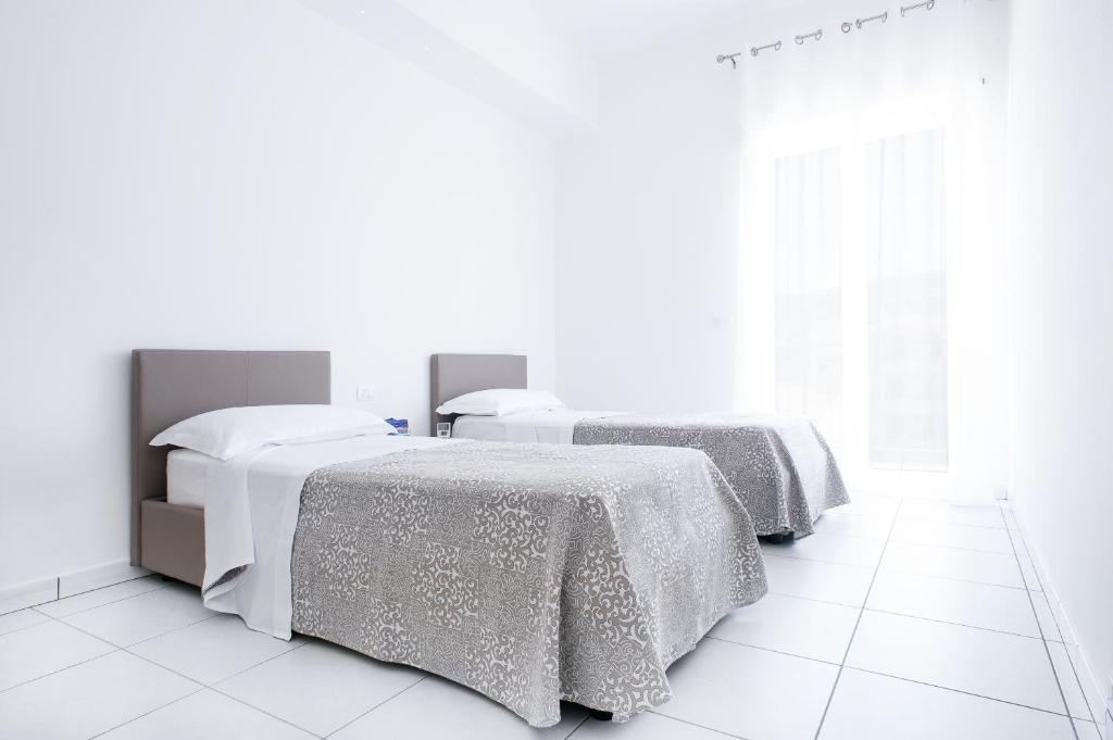 Cette chambre blanche dispose de 2 lits et de sols blancs. dans l'établissement Vuelle Residence Apartments, à Capo dʼOrlando