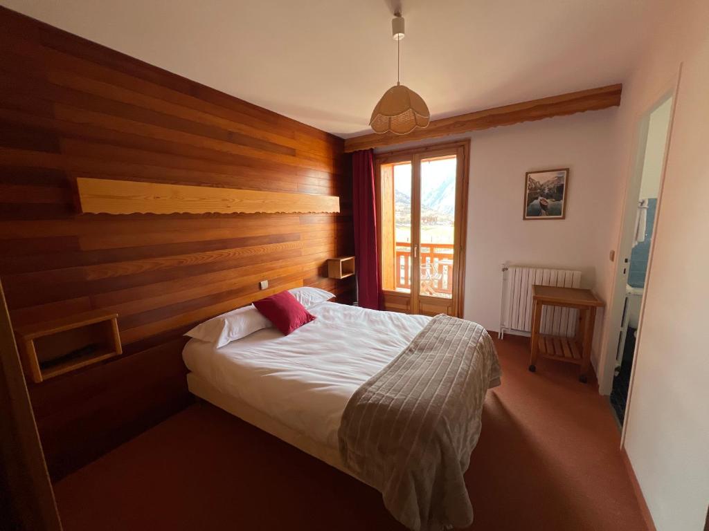 une chambre avec un lit avec une tête de lit en bois dans l'établissement Hôtel Restaurant La Pendine, à Puy-Saint-Vincent 23 autres photos
