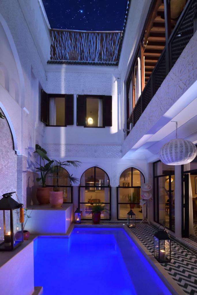 - une piscine dans une maison avec un éclairage bleu dans l'établissement Riad Palau Marrakech, à Marrakech