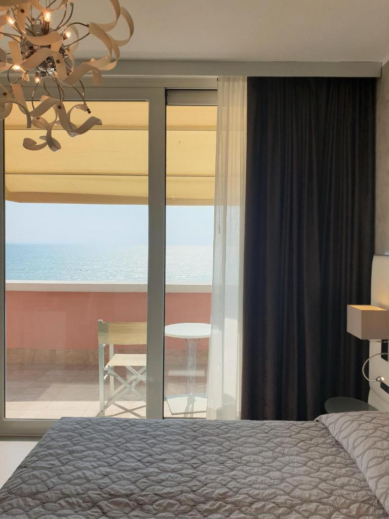 une chambre avec un lit et une vue sur l'océan dans l'établissement Grande Albergo Marin, à Lignano Sabbiadoro