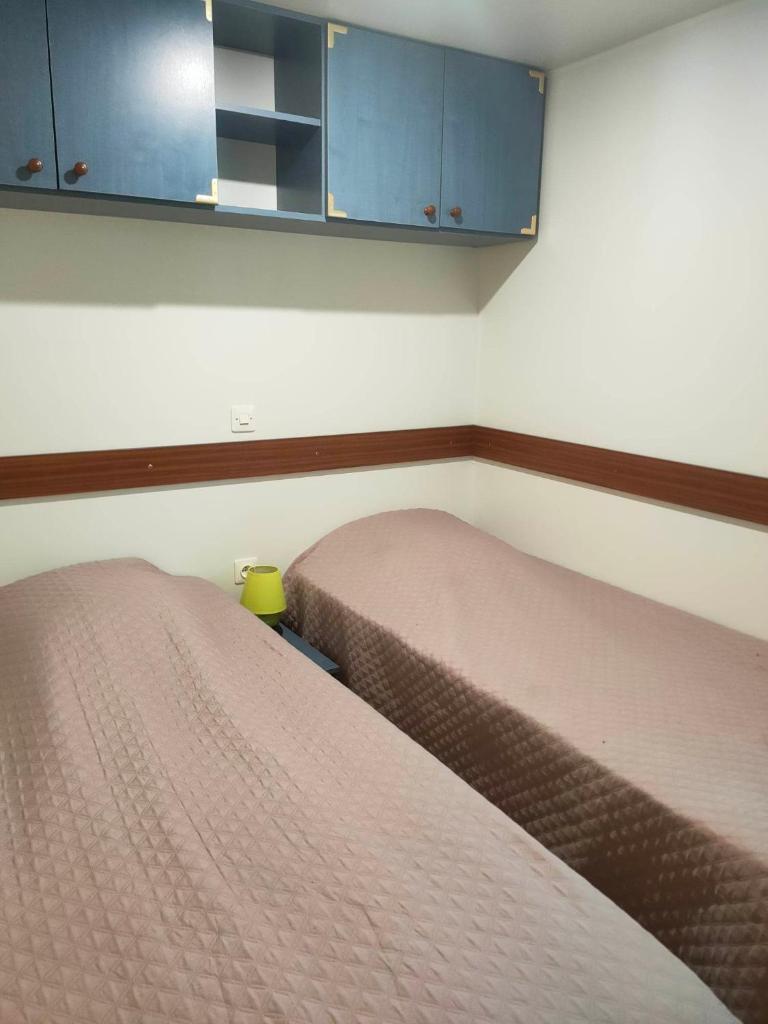 deux lits côte à côte dans une pièce dans l'établissement Mobil-home au camping La Lande à Mimizan n°507, à Mimizan 16 autres photos