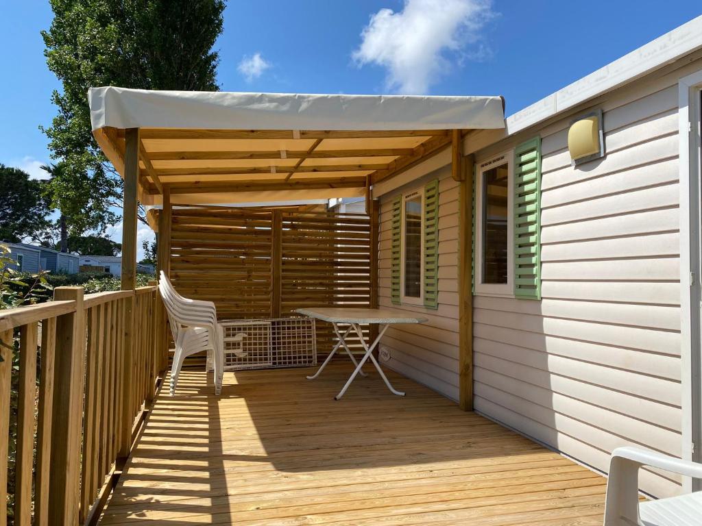 une terrasse en bois avec une table et un auvent dans l'établissement MOBILE HOME 6 PERSONNES, à Port-la-Nouvelle