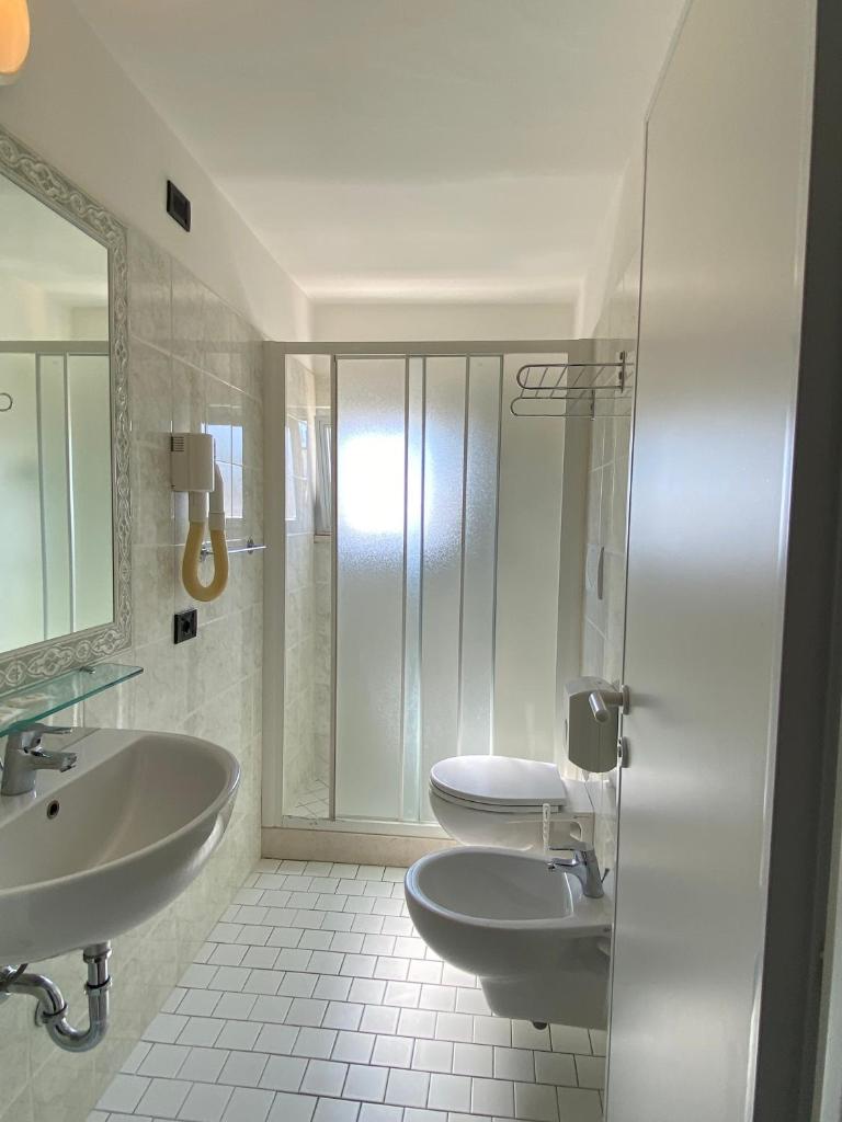 une salle de bain blanche avec deux lavabos et une douche dans l'établissement Hotel Stella Alpina, à Rimini
