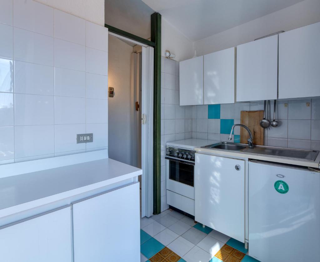 une cuisine avec des armoires blanches et un évier dans l'établissement Villino Mimma, à Campu Longu