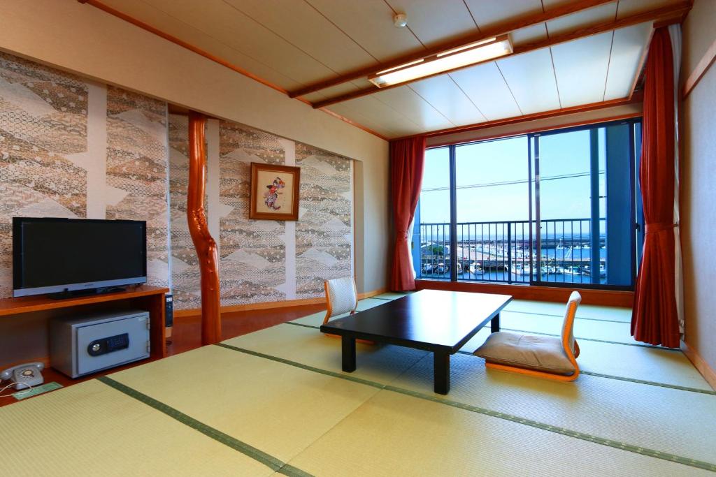 un salon avec une table et une grande fenêtre dans l'établissement Hotel Seikaisou, à Minamichita