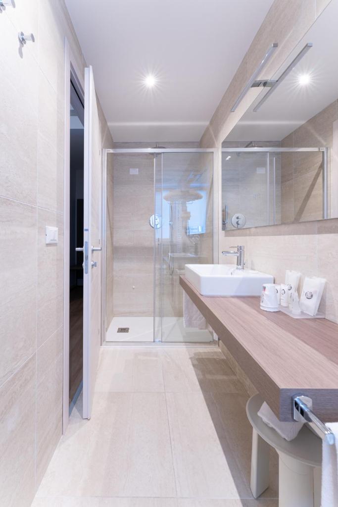 une salle de bain avec un lavabo et une douche en verre dans l'établissement Hotel Excelsior, à Lido di Jesolo