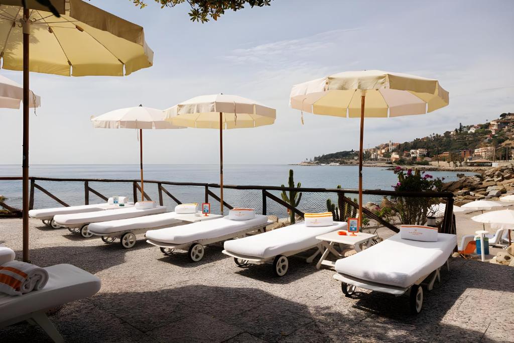 - une rangée de chaises longues avec parasols et vue sur l'océan dans l'établissement Grand Hotel Del Mare Resort & Spa, à Bordighera