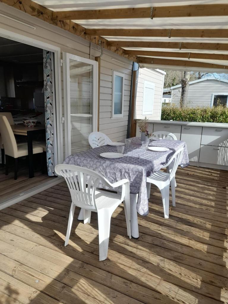 une table et des chaises blanches sur une terrasse dans l'établissement Mobilhome 422 3ch/1 sdb camping 4* La Réserve SIBLU Gastes, à Gastes