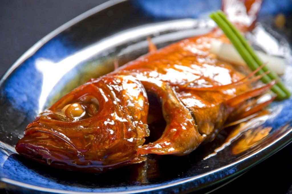 une assiette bleue avec un morceau de poulet et de la sauce dans l'établissement Hamanoyu, à Higashiizu
