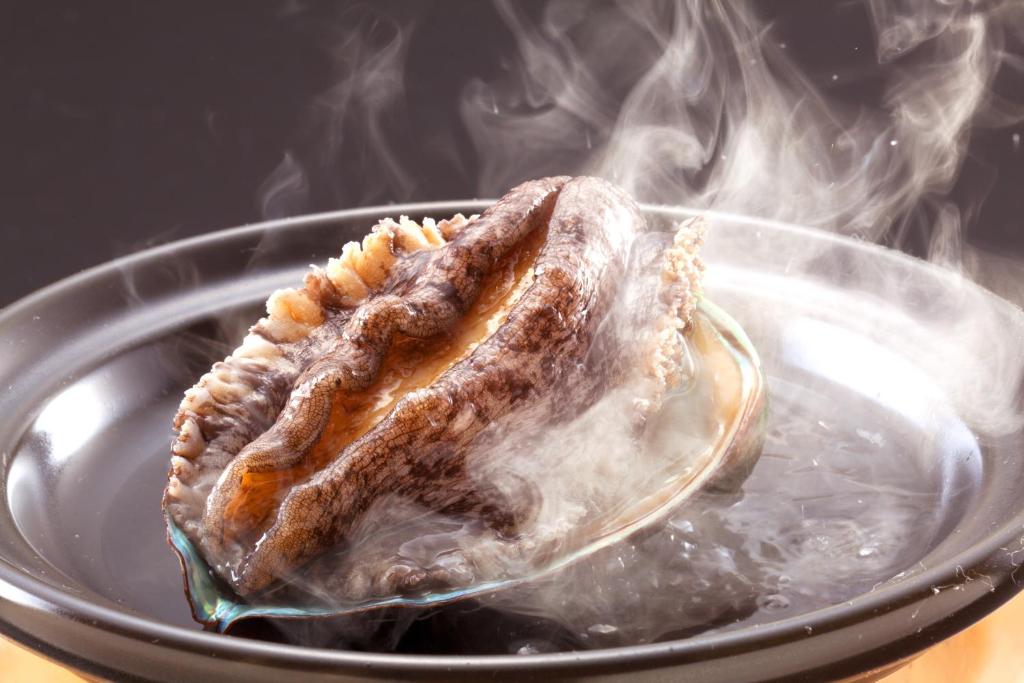 un morceau de viande sur une assiette avec de la fumée dans l'établissement Hamanoyu, à Higashiizu