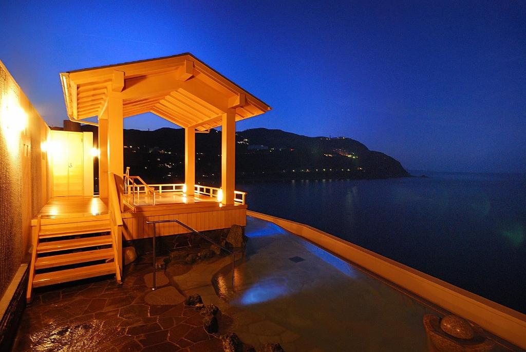 un bâtiment avec un belvédère sur l'eau la nuit dans l'établissement Hamanoyu, à Higashiizu 13 autres photos