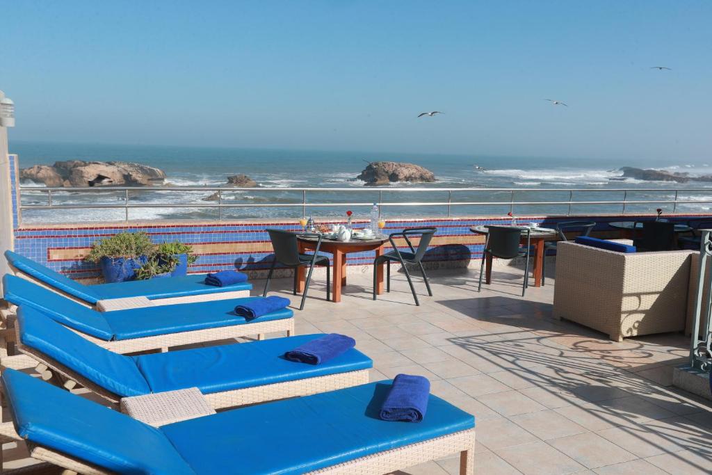 d'une terrasse avec des chaises bleues et une table donnant sur l'océan. dans l'établissement Riad Perle D'Eau, à Essaouira