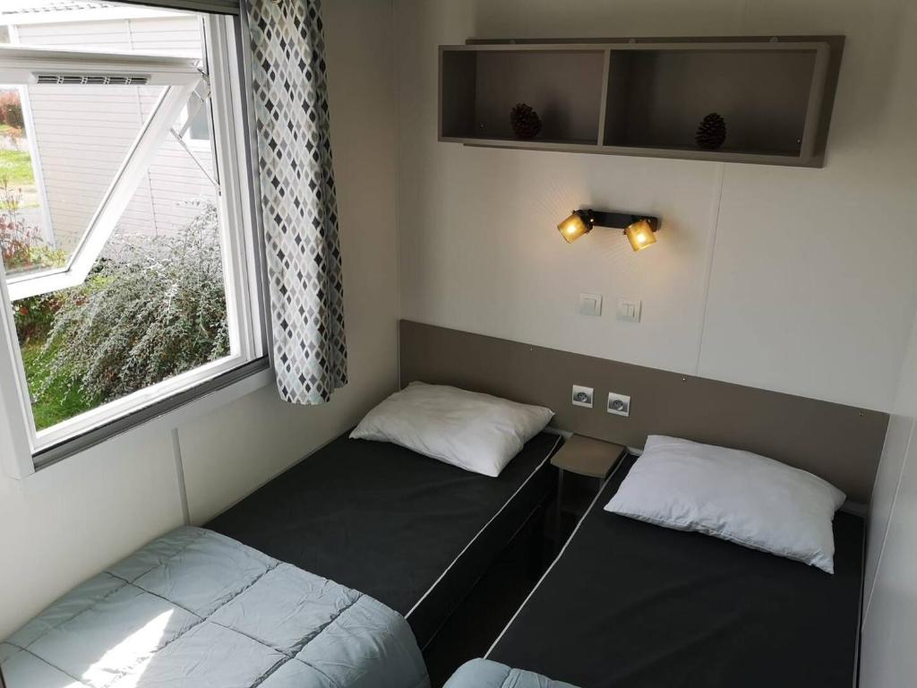 une petite chambre avec deux lits et une fenêtre dans l'établissement CHEZ LOLO MH 3CH 2SDB CLIM 8p VUE CHAMPS EMPLACEMENT CALME, à Onzain