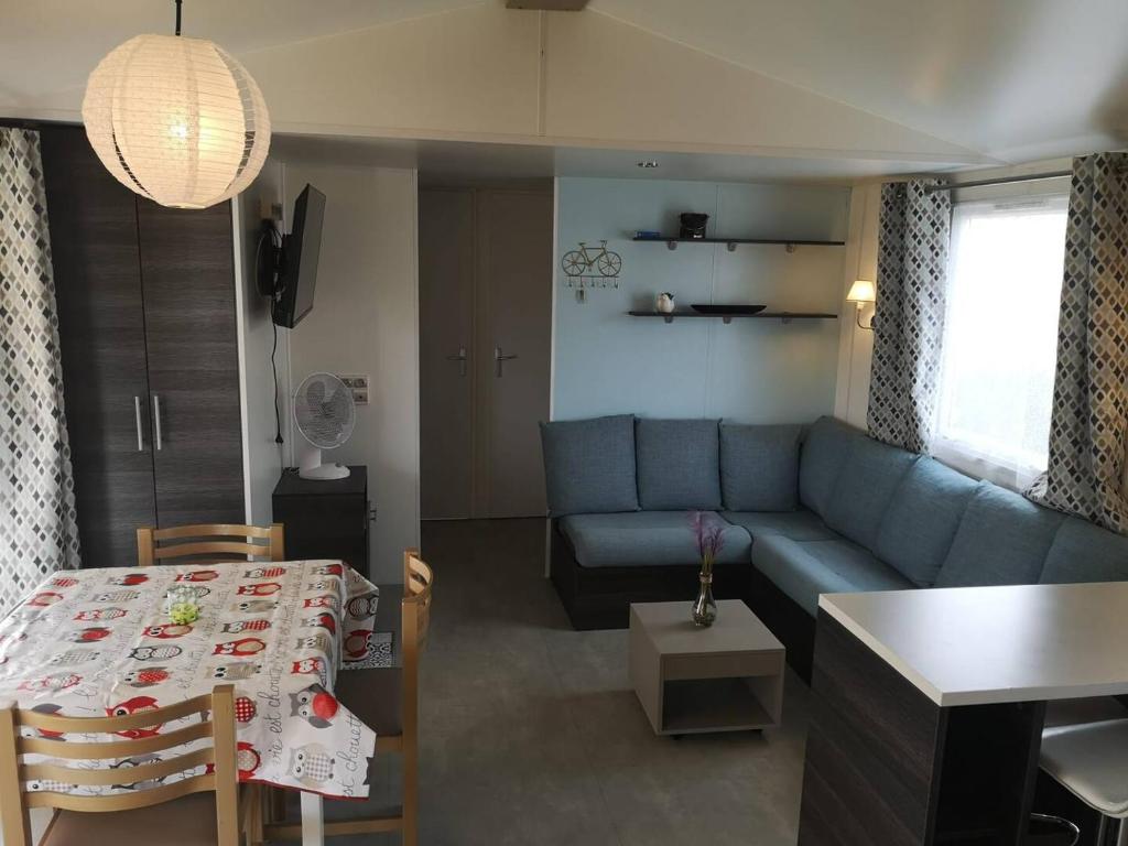 un salon avec un canapé bleu et une table dans l'établissement CHEZ LOLO MH 3CH 2SDB CLIM 8p VUE CHAMPS EMPLACEMENT CALME, à Onzain