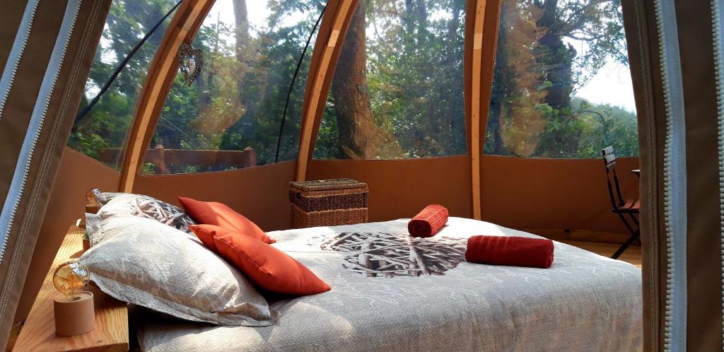 un lit dans une chambre avec une grande fenêtre dans l'établissement Le Mobil'Dôme à Marie, à Cambounès