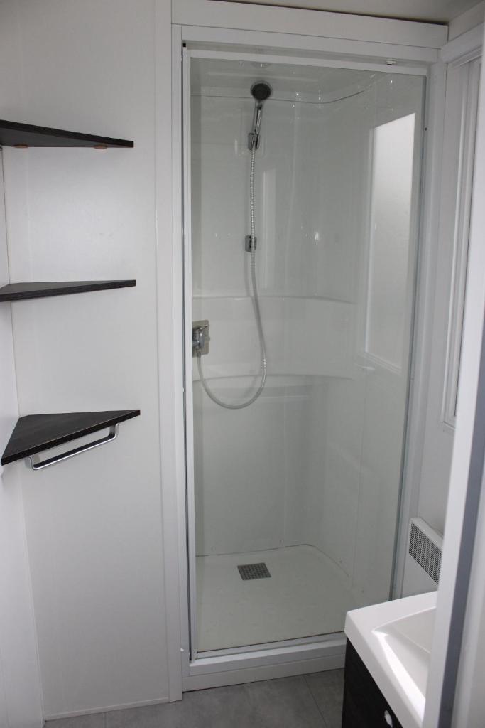 une douche avec une porte vitrée dans une salle de bain dans l'établissement Mobil-home, à Litteau