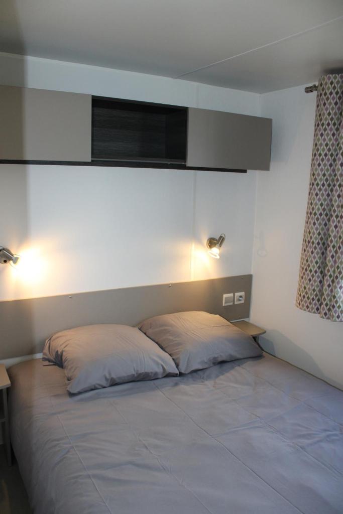 - un lit dans une chambre avec 2 oreillers dans l'établissement Mobil-home, à Litteau