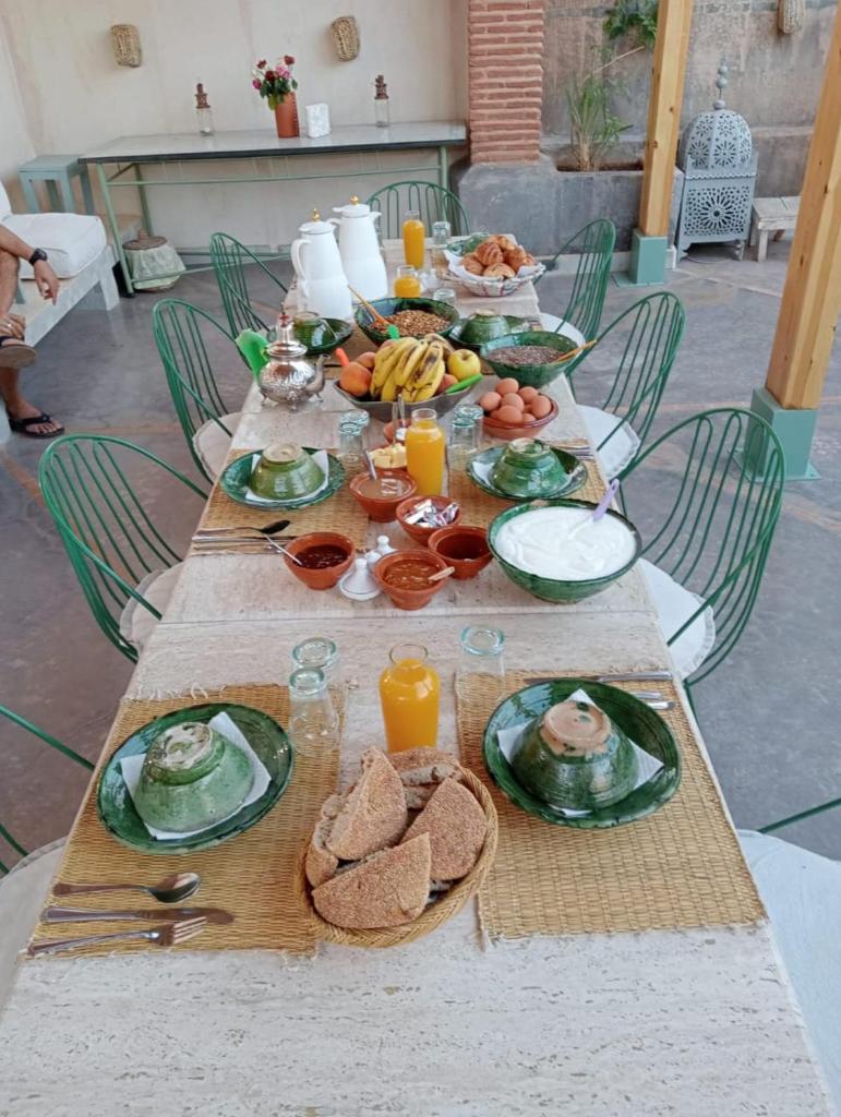 une table en bois avec des assiettes de nourriture dessus dans l'établissement Riad Chambres D'Amis Marrakech, à Marrakech