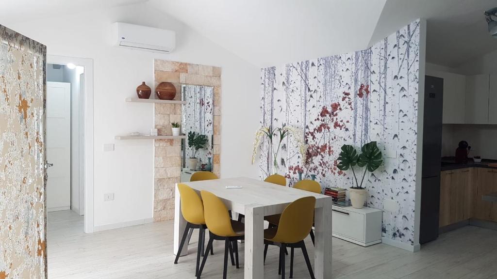 une salle à manger avec une table blanche et des chaises jaunes dans l'établissement VILLA ILARIA con piscina privata a 350 mt spiaggia di sabbia, à Tertenìa