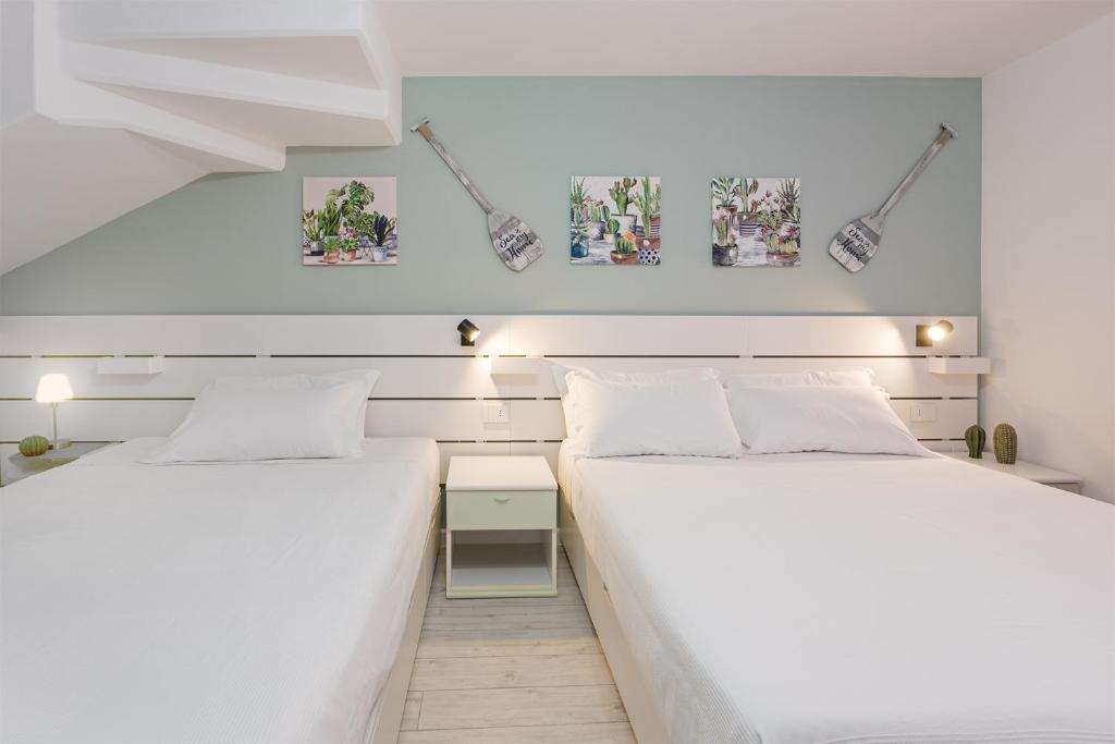 deux lits dans une chambre aux murs blancs dans l'établissement VILLA ILARIA con piscina privata a 350 mt spiaggia di sabbia, à Tertenìa