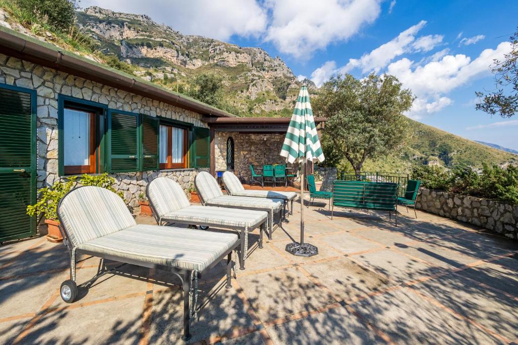 une rangée de chaises et un parasol sur une terrasse dans l'établissement Seacliff Heaven - De Vivo Realty Positano, à Arola