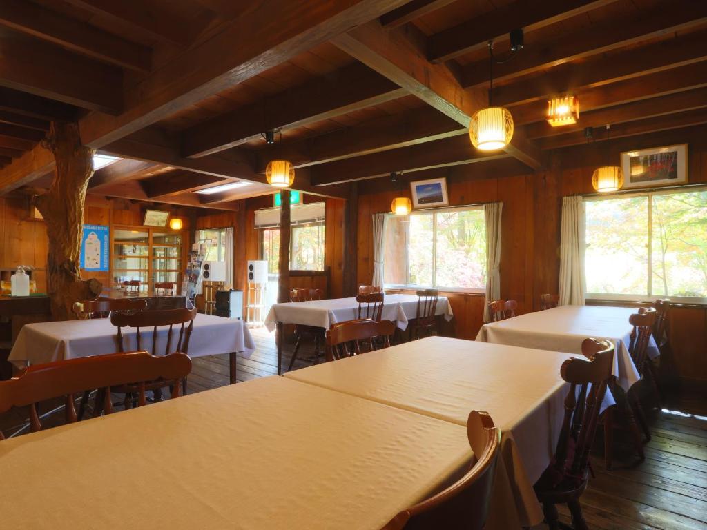 une salle à manger avec tables, chaises et fenêtres dans l'établissement 雀の宿 やぐら, à Matsumoto