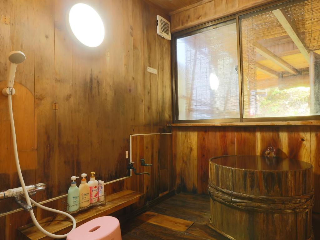 La salle de bains en bois est pourvue d'une baignoire en bois et d'une fenêtre. dans l'établissement 雀の宿 やぐら, à Matsumoto 52 autres photos