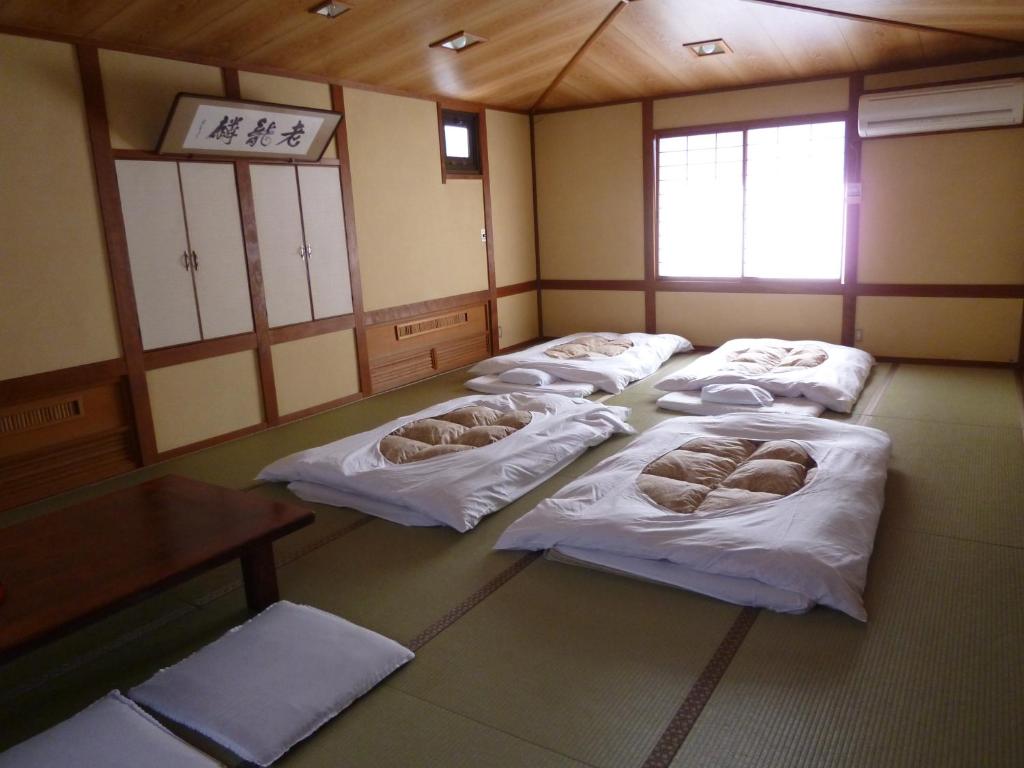 Cette chambre comprend 4 lits avec des draps blancs. dans l'établissement Iwamura Sanso, à Ena