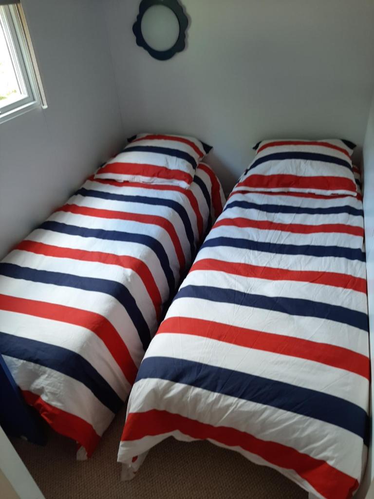 Cette chambre comprend 2 lits avec des oreillers à rayures rouges et bleus. dans l'établissement Mobil home, à Montrigaud