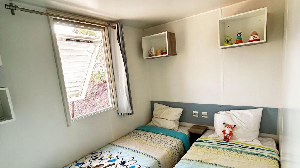 une petite chambre avec deux lits et une fenêtre dans l'établissement Camping Tikayan Les Cigales - Maeva, au Muy