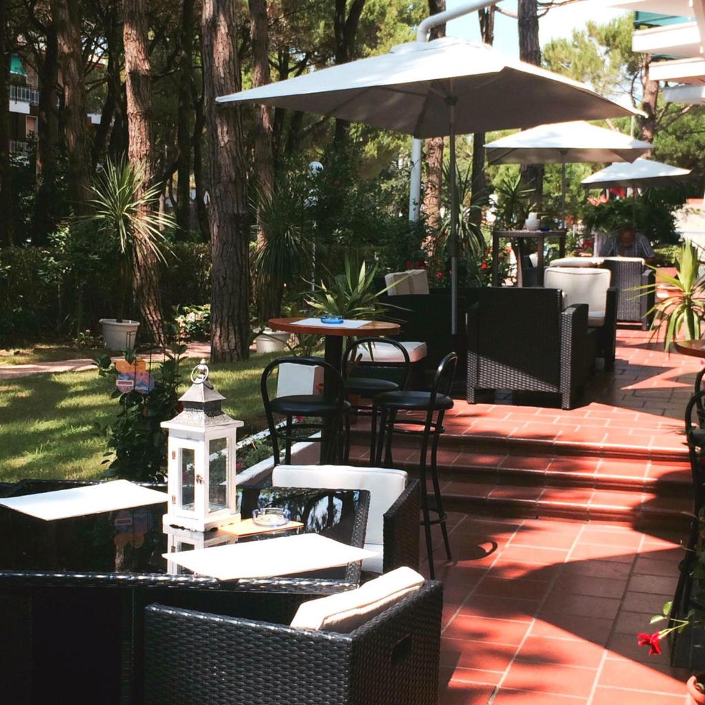 un patio avec tables, chaises et un parasol dans l'établissement Hotel King, à Lido di Jesolo