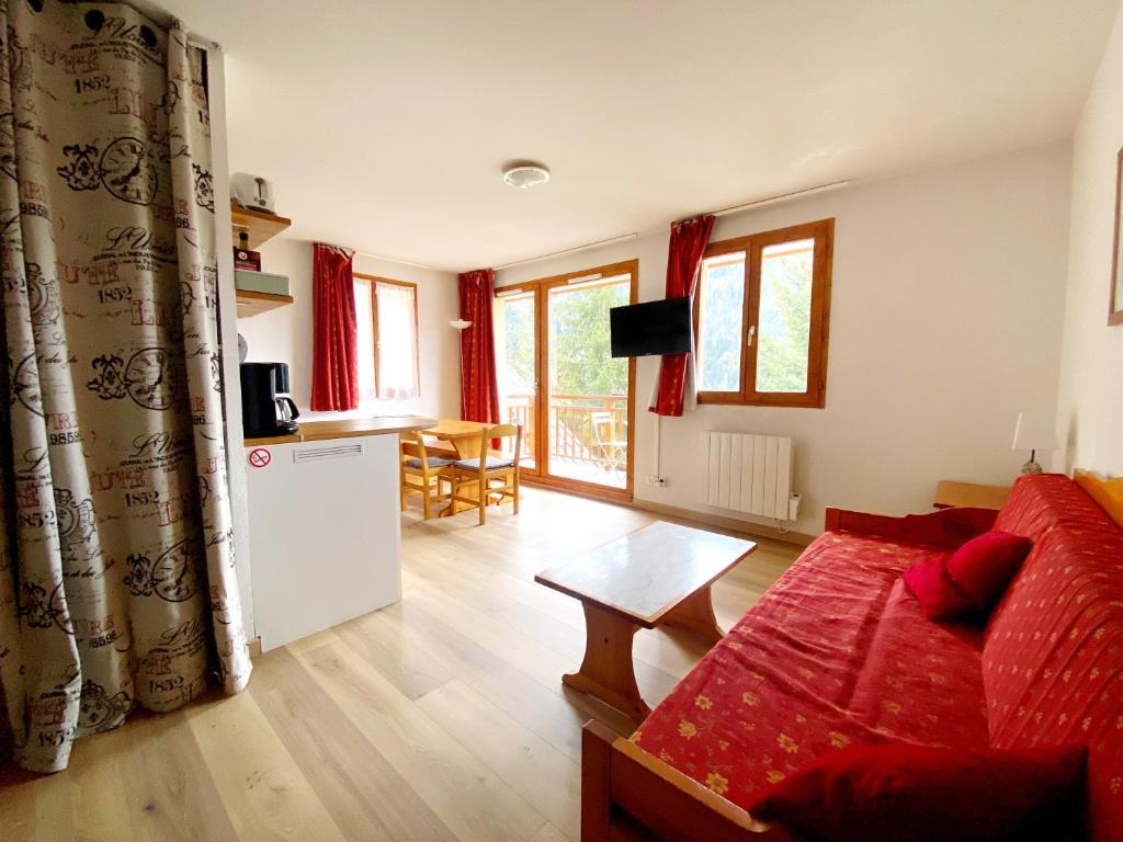un salon avec un canapé rouge et une cuisine dans l'établissement Appartement Ski Pied de Pistes - Valfréjus, à Modane