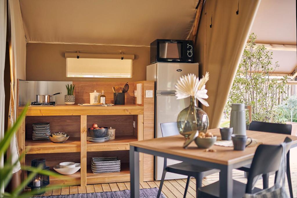 une cuisine avec une table et un réfrigérateur dans l'établissement Le Vallon aux merlettes, à Matignon