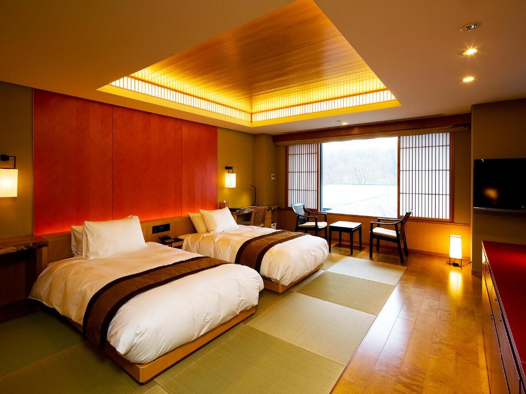 une chambre d'hôtel avec deux lits et une salle à manger dans l'établissement 竹泉荘 Chikusenso Onsen, à Zao