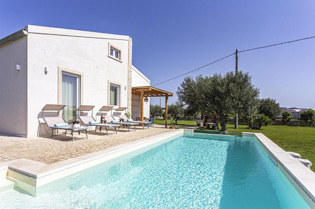 une piscine avec des chaises et une maison dans l'établissement Villa Ginevra by Villa Plus, à Ispica